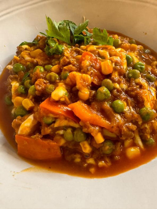 Dieses Bild zeigt Dominika Mörtels "Blitz Kürbis con Carne" – eine gesunde, proteinreiche Mahlzeit mit Hackfleisch, Kürbis, Erbsen, Mais und Mozzarella in einer würzigen Tomatensauce.